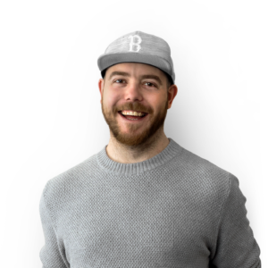 Man with light grey new ere style baseball cap, brown / ginger beard and light grey jumper