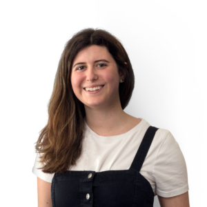 Young lady with long black hair over her right shoulder fashioning a black dungaree style ad white t-shirt